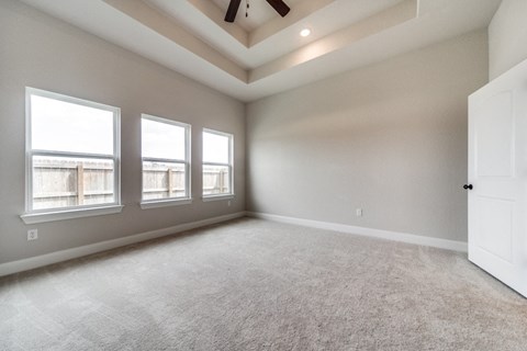 an empty living room with three windows and a ceiling fan