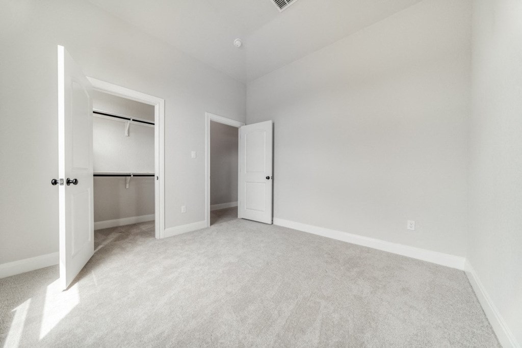 an empty bedroom with a closet and a door to the bathroom