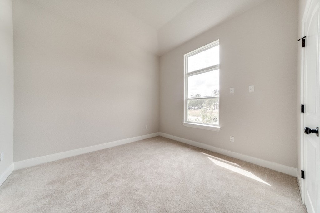 an empty room with white carpet and a window