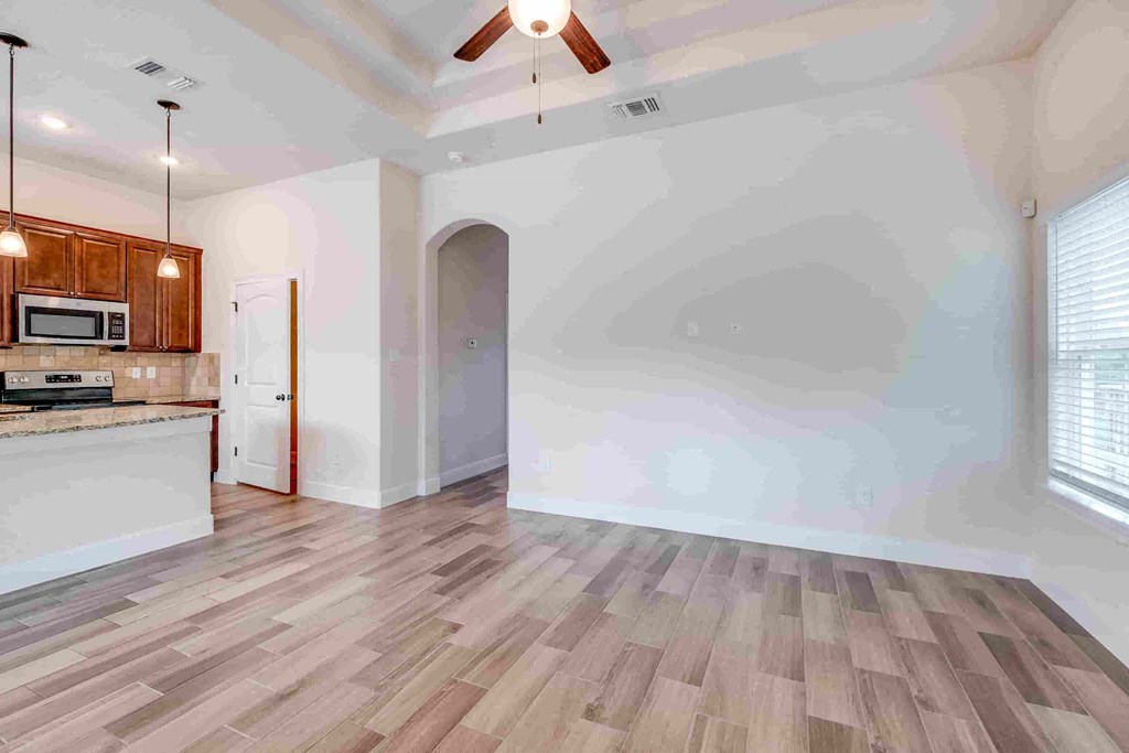 an empty living room and kitchen with wood floors and white walls