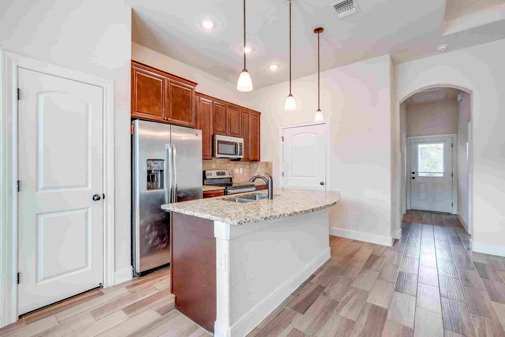 a kitchen with a large island and a stainless steel refrigerator