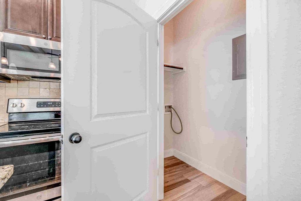 a white door leading to a kitchen with a stove and microwave
