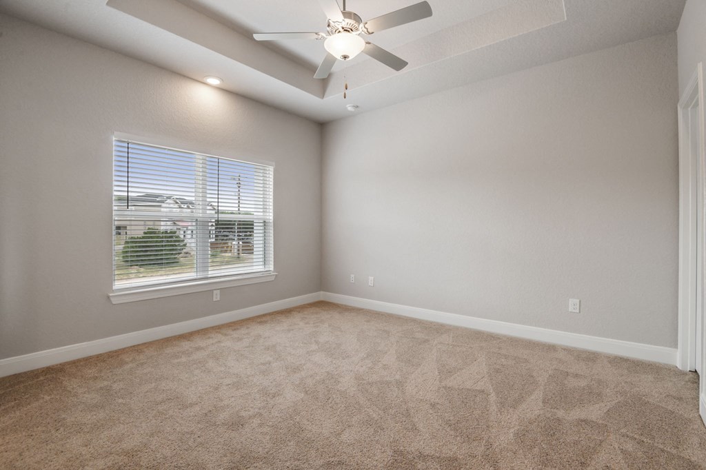 an empty living room with a window and a ceiling fan