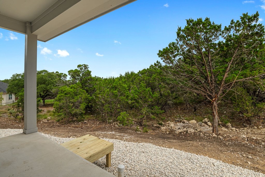 a view of the woods from a porch with a bench