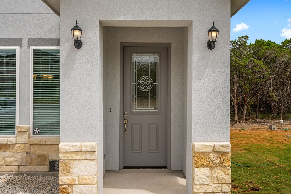 the front door of a house with a gray door and two lamps on either side