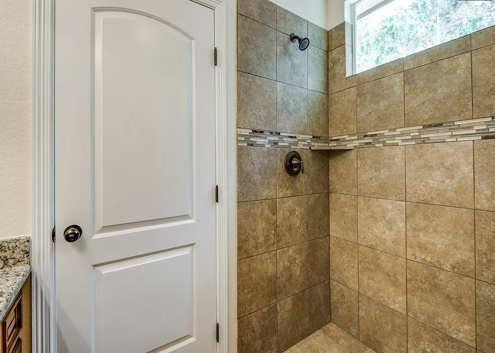 a bathroom with a shower and a white door