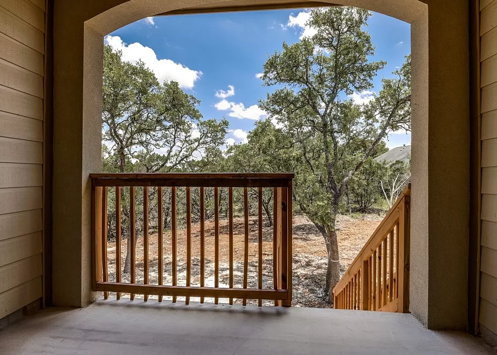 a balcony with a view of a yard and trees