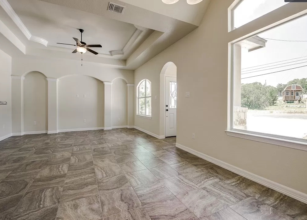 an empty living room with a ceiling fan and a large window
