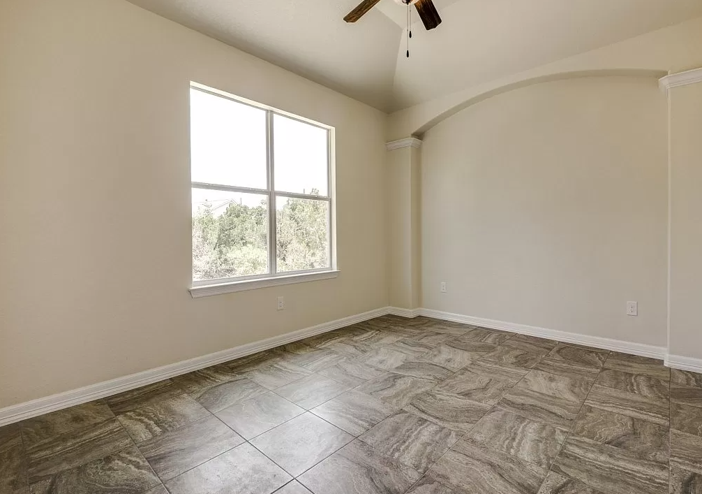 an empty living room with a large window and wood flooring