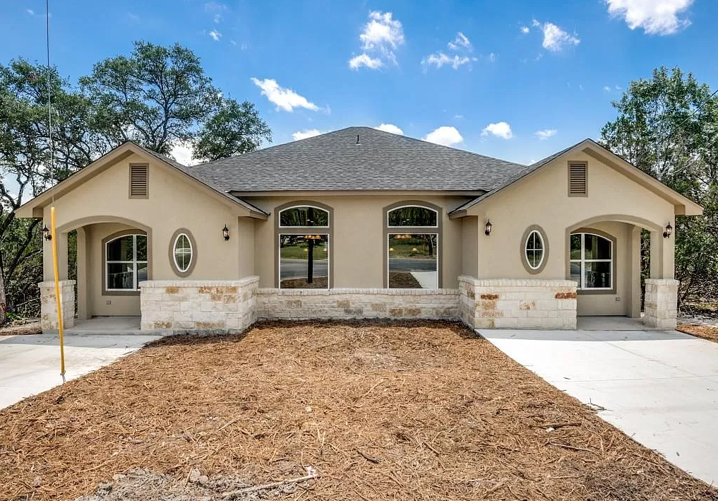 a beige house with a large yard and a driveway