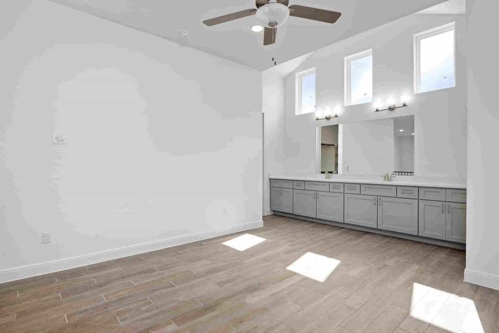 an empty bedroom with a ceiling fan and a mirror