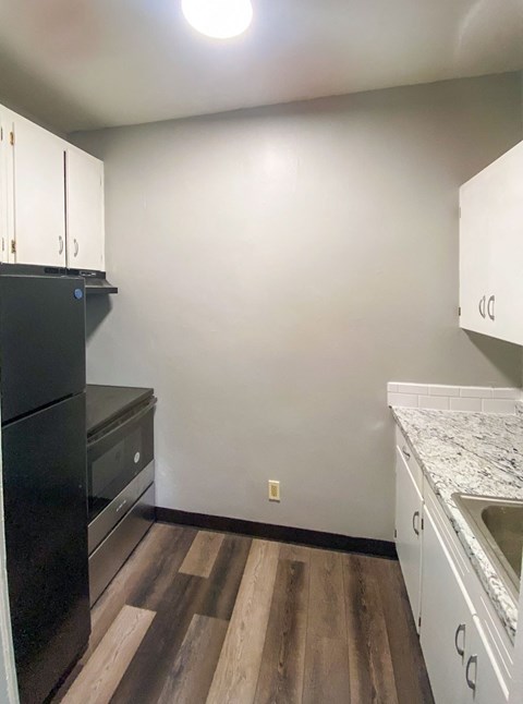 a kitchen with white cabinets and black appliances and wood floors
