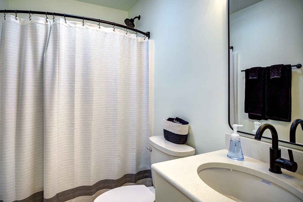 A bathroom with a white sink, toilet, and a shower curtain.