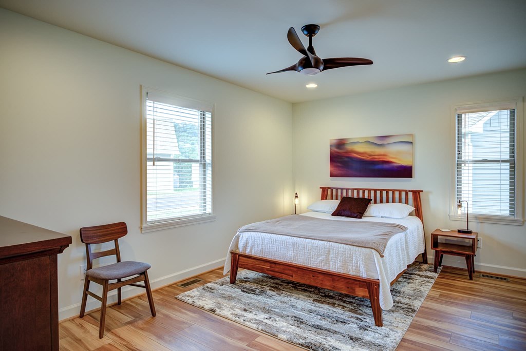 A bedroom with a bed, chair, and painting on the wall.