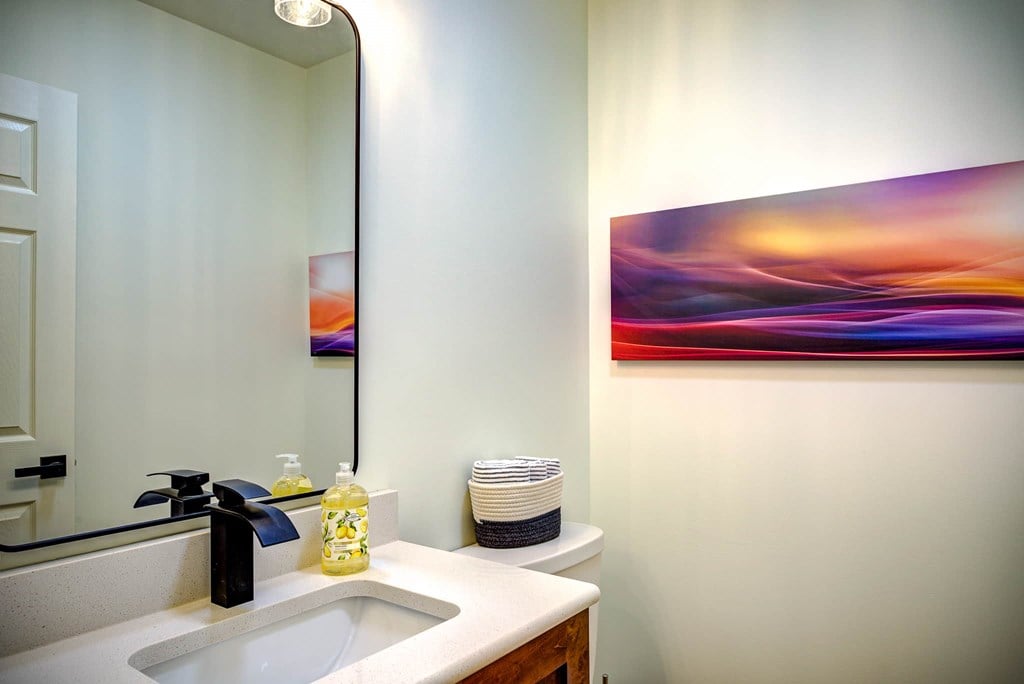 A bathroom with a sink, mirror, and a painting on the wall.