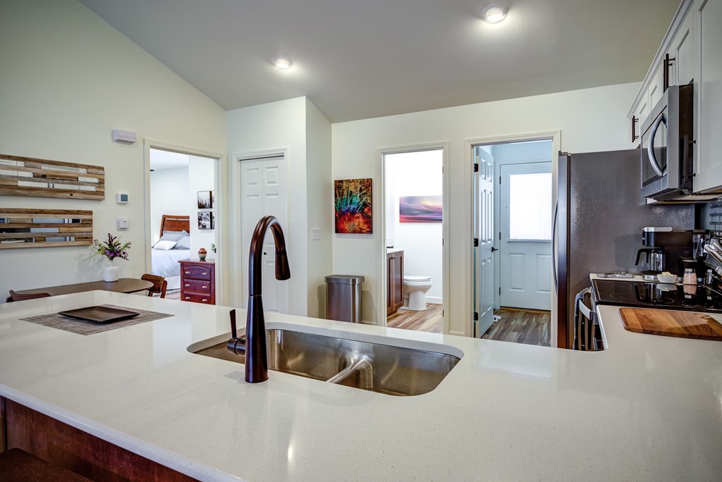 A modern kitchen with a white countertop and a stainless steel sink.