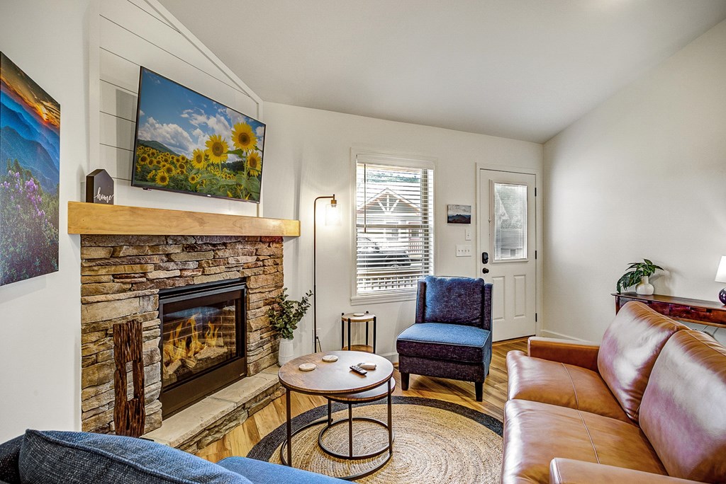 A living room with a fireplace and a painting of a sunflower field on the wall.
