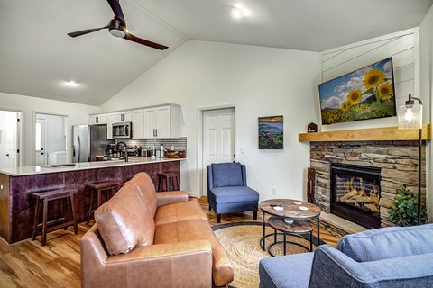 A living room with a brown leather couch and a fireplace.