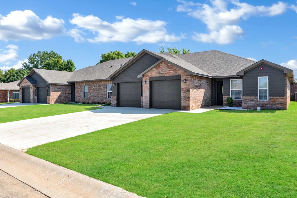 a brick house with a lawn and a driveway