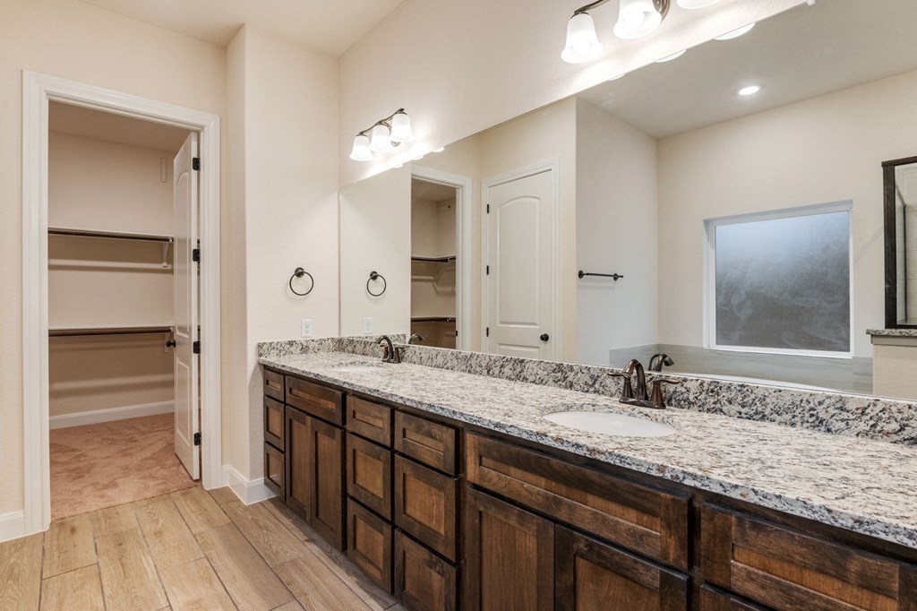 the retreat guest bathroom with granite counter tops and wooden cabinets