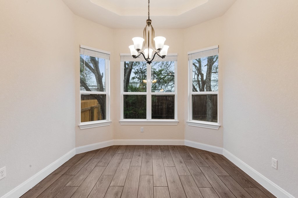 an empty living room with windows and a chandelier