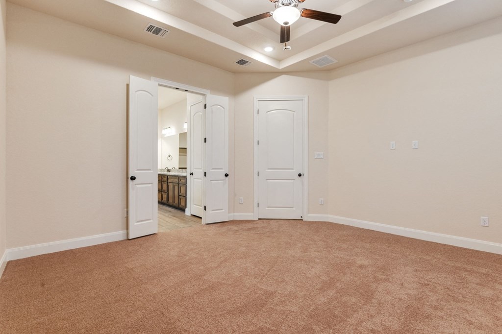 an empty living room with a ceiling fan and a bathroom
