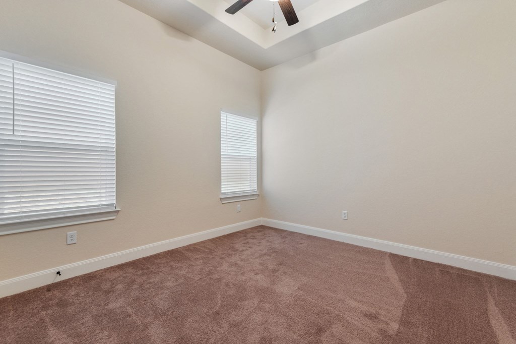 the spacious living room with carpet and two windows