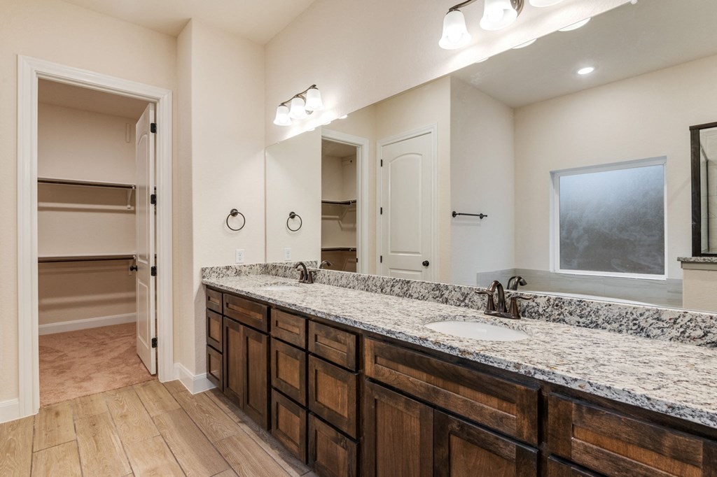 the retreat guest bathroom with granite counter tops and wooden cabinets
