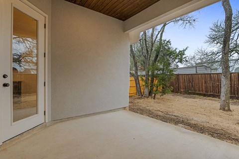the covered patio on the back of a house with a sliding glass door