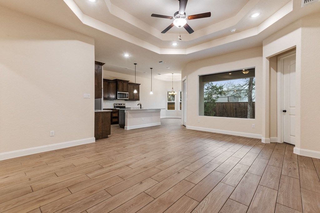 an empty living room with a ceiling fan and a kitchen