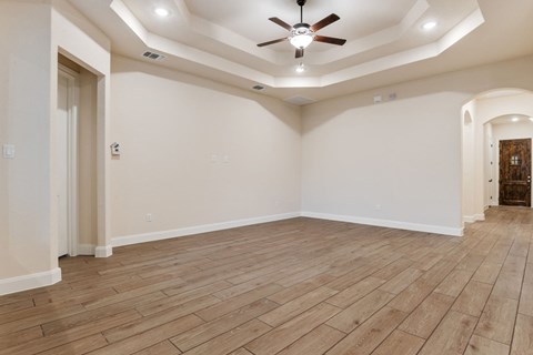 the living room with wood flooring and a ceiling fan