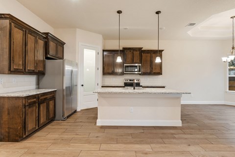 a kitchen with a large island and a stainless steel refrigerator