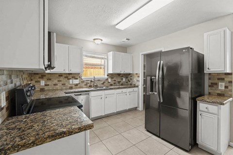 a kitchen with white cabinets and a stainless steel refrigerator