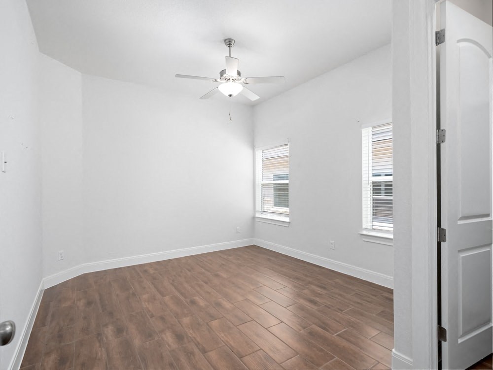 an empty living room with wood flooring and a ceiling fan