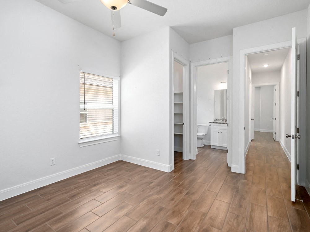 a living room with white walls and wood flooring and a ceiling fan