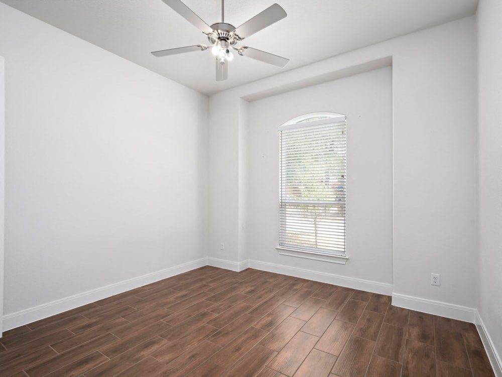 an empty living room with wood floors and a ceiling fan