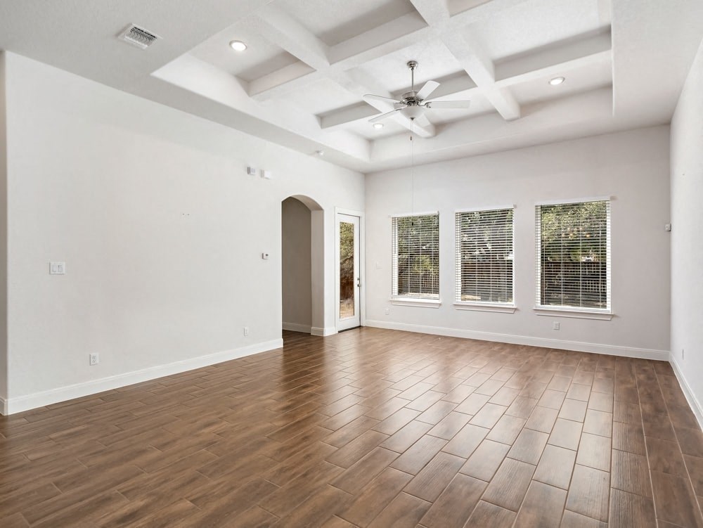 an empty living room with wood floors and a ceiling fan