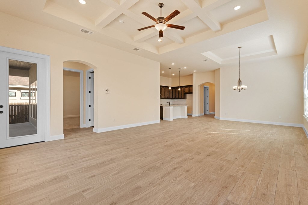 an empty living room with a ceiling fan and a kitchen