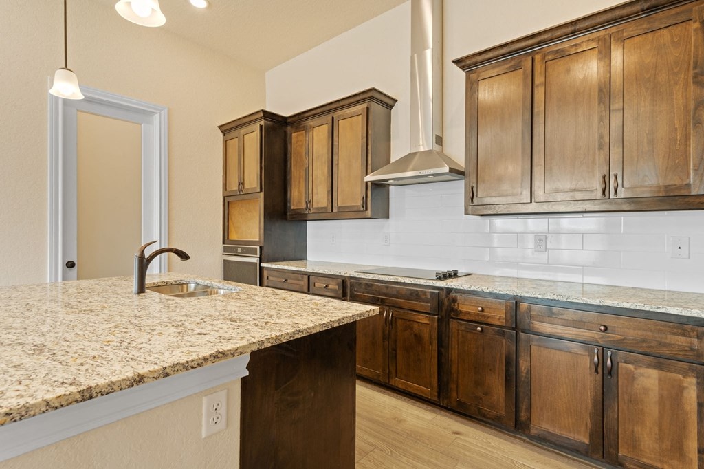 a kitchen with wooden cabinets and granite counter tops and a sink