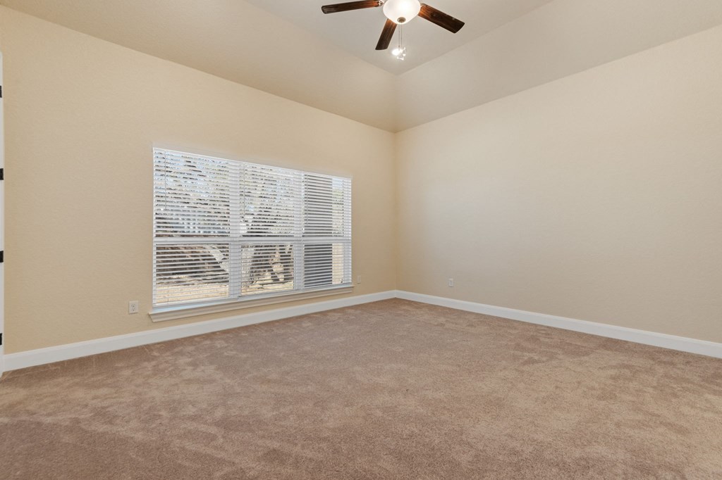 an empty living room with a window and a ceiling fan