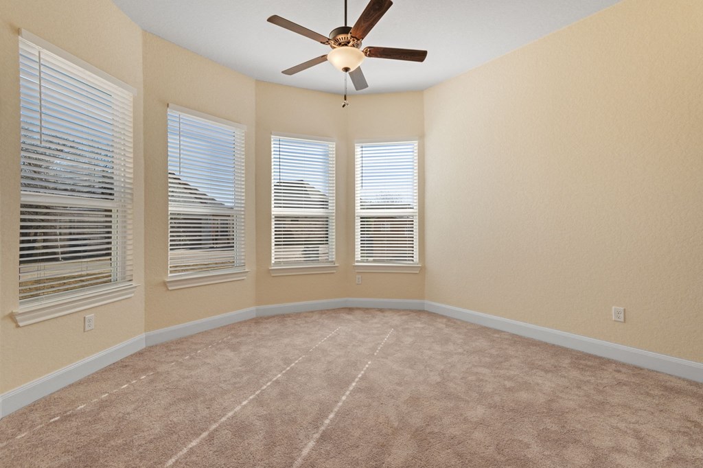an empty living room with windows and a ceiling fan