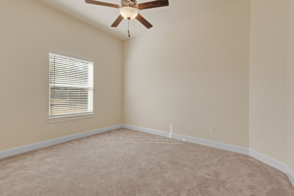 an empty living room with a ceiling fan and a window