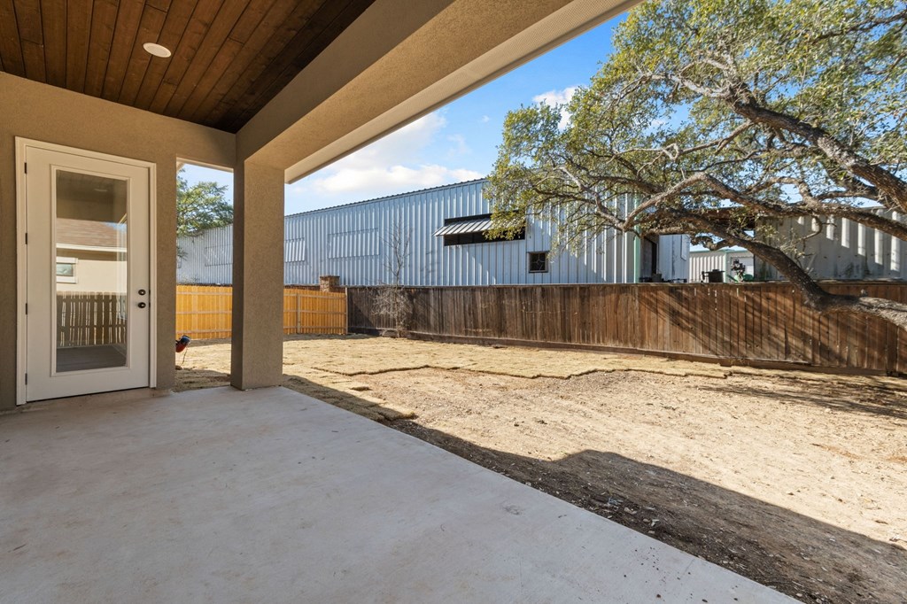 the private patio of a house with a fence and a tree