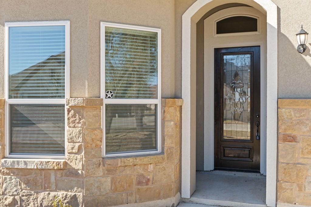 the front door of a home with a glass window and a wooden door