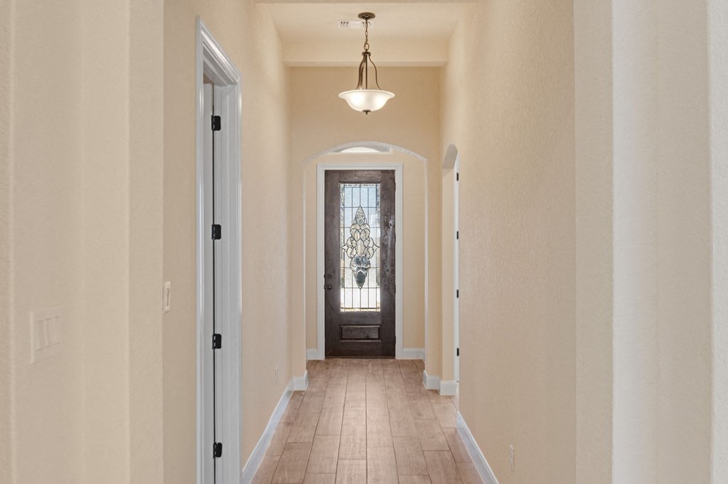 a long hallway with a door to a room with a window