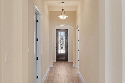 a long hallway with a door to a room with a window