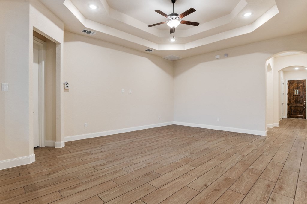 the living room with wood flooring and a ceiling fan
