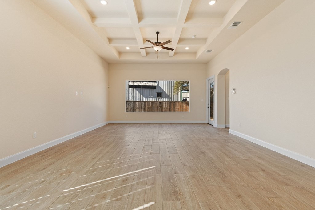 an empty living room with wood floors and a ceiling fan