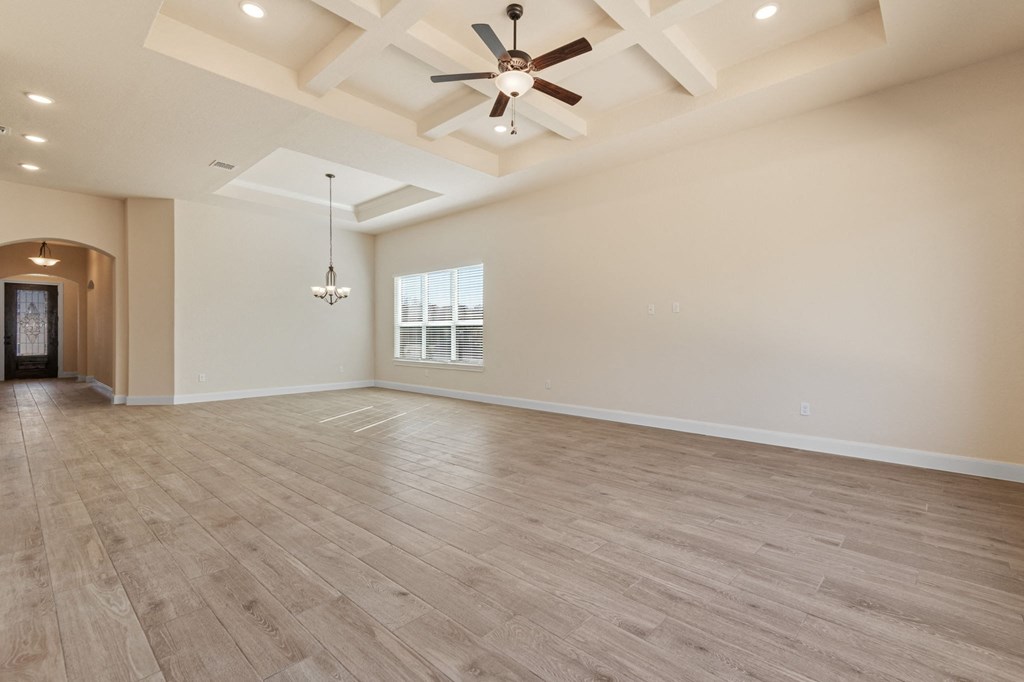 an empty living room with a ceiling fan and a window