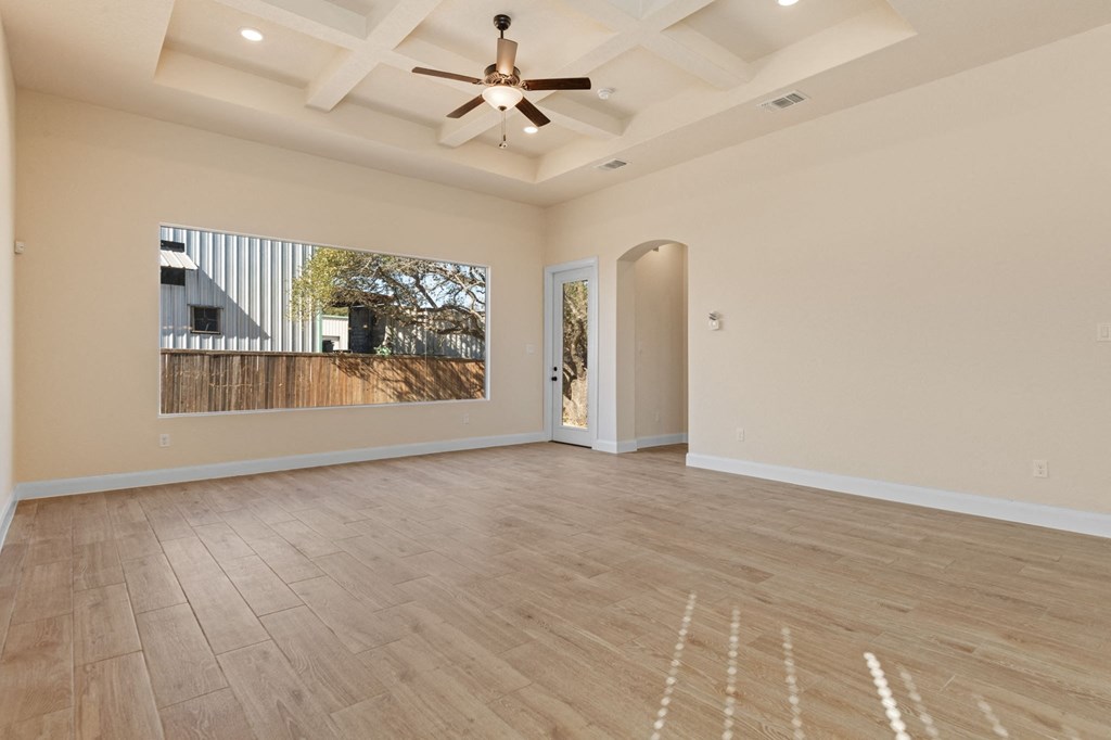 an empty living room with a ceiling fan and a window